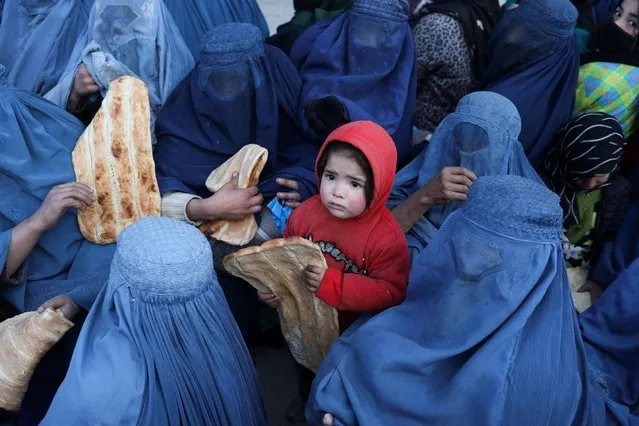 An Afghan child holds bread in front of a bakery in Kabul, Afghanistan, January 31, 2022. (Photo by Ali Khara/Reuters)