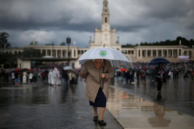A pilgrim carrying an umbrella waits to attend a candlelight vigil, as pilgrims attend the 99th anniversary of the appearance of the Virgin Mary to three shepherd children, at the Catholic shrine of Fatima, Portugal May 12, 2016. (Photo by Rafael Marchante/Reuters)