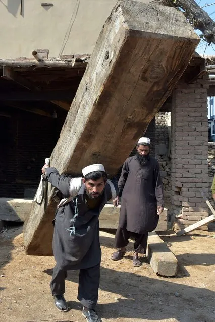 A labourer shifts a wooden beam in Peshawar on February 24, 2022. (Photo by Abdul Majeed/AFP Photo)