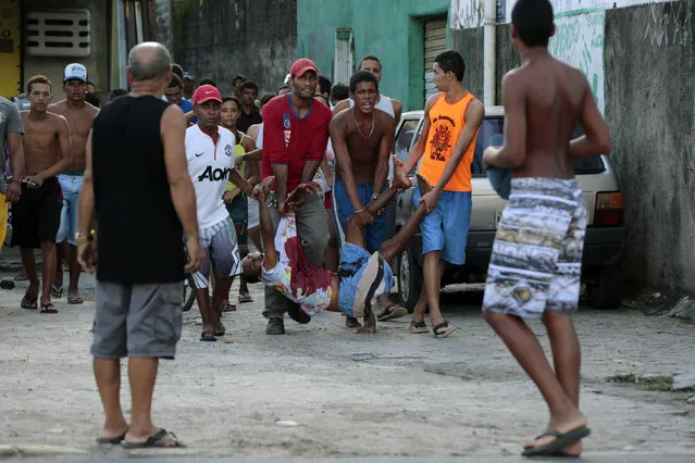 Residents carry an injured man after a store was looted during a police strike in Recife, May 15, 2014. Road blocks and marches hit Brazilian cities on Thursday as disparate groups criticized spending on the upcoming World Cup soccer tournament and sought to revive a call for better public services that swept the country last June. Pernambuco state police called a strike over their demands for better salaries and benefits. (Photo by Alexandre Gondim/Reuters)