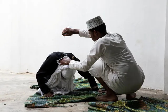 A sheikh tries to rouse a woman by pouring water on her neck in Zanzibar City, Tanzania, February 17, 2019. The woman believes she is possessed by supernatural spirits like djinns. (Photo by Nicky Woo/Reuters)