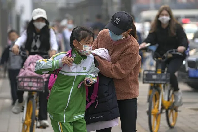 A woman wearing a face mask to help protect from the coronavirus sends a masked child to school, Monday, April 11, 2022, in Beijing. (Photo by Andy Wong/AP Photo)
