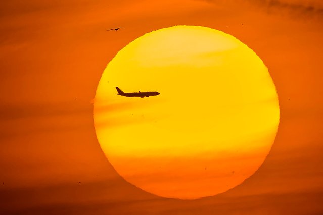 A passenger aircraft is silhouetted by the setting sun in the Eminonu district of Istanbul on July 24, 2024. (Photo by Yasin Akgul/AFP Photo)