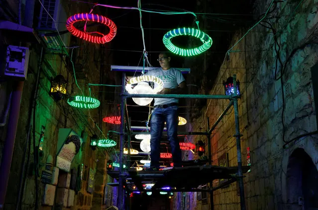 A Palestinian man hangs decorations for the upcoming holy month of Ramadan outside his home in Jerusalem's Old City, June 4, 2016. (Photo by Ammar Awad/Reuters)