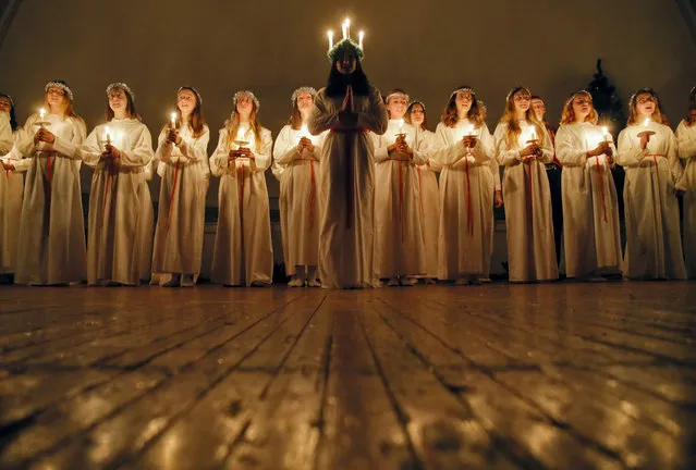 Young women sing carols as they hold candles to celebrate St. Lucia's Day in the Evangelical Lutheran Church of Saint Katarina in St.Petersburg, Russia, Friday, December 13, 2019. The Church was built in the 19th century by and for Swedish expatriates in Saint Petersburg, and it is usually called the Swedish church. In Soviet era the Church used as a sport hall. St. Lucia is the patron saint of vision. (Photo by Dmitri Lovetsky/AP Photo)