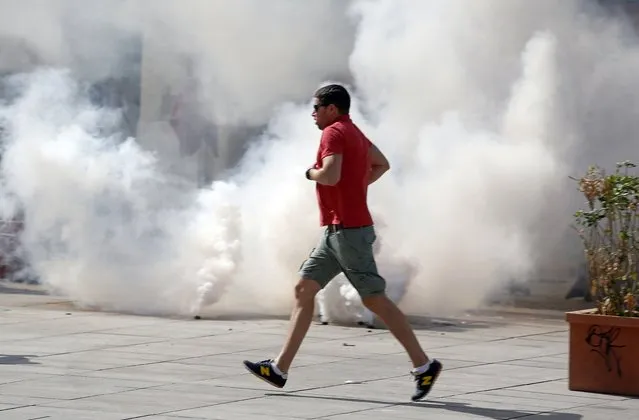 An England supporter runs past tear gas through the streets in downtown Marseille, France, Saturiday, June 11, 2016. Two nights of clashes between England supporters, French police and locals have marked the build up to Saturday's Euro 2016 soccer Championship match between England and Russia. (Photo by Darko Bandic/AP Photo)