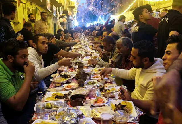 Residents of Ezbet Hamada gather to eat during Iftar, a meal to end their fast at sunset, during the holy fasting month of Ramadan in Mataria, Cairo, Egypt, April 16, 2022. (Photo by Fatma Fahmy/Reuters)
