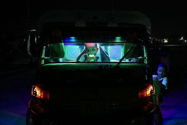 An auto driver's children wait inside the auto during the Ram Leela fair at a ground in Varanasi on October 8, 2024. (Photo by Niharika Kulkarni/AFP Photo)