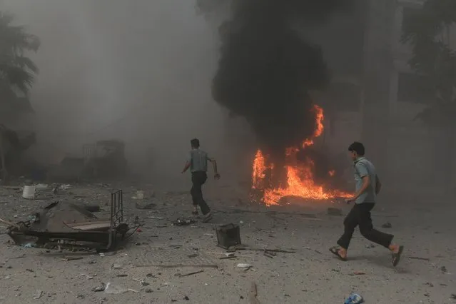 Men run at a site hit by what activists said were air strikes by forces loyal to Syria's President Bashar al-Assad on a marketplace in the Douma neighborhood of Damascus, Syria August 16, 2015. (Photo by Bassam Khabieh/Reuters)