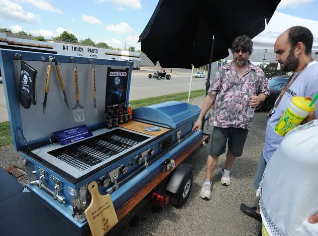 Nightmare Cruisers hearse club president Steve Frey, left, shows off his “Open Casket Bar and Grill” to Mackinley and Erika Watson, of Pontiac, Mich., during the inaugural Scream Cruise on Sunday, August 16, 2015. Hosted by the Nightmare Cruisers Hearse Club, the inaugural Scream Cruise screeched into Pontiac, with its collection of funeral coaches, skull-mobiles, rat rods and motorcycles. (Photo by Brandy Baker/The Detroit News via AP Photo)
