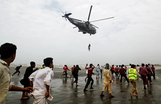A Pakistan Navy helicopter evacuates a recovered body of a victim who drowned over Clifton beach in Karachi, Pakistan,  Thursday, July 31, 2014. Scores of people drowned despite a ban on entering and bathing in the sea due to high tides, after thousands of people turned up on various beaches of Karachi to celebrate Muslims festive day of Eid. (Photo by Fareed Khan/AP Photo)