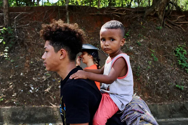 A man carries his son as he walks along with other migrants in a caravan after growing impatience of waiting for the humanitarian visa to cross the country to reach the U.S. border, in Tapachula, Mexico on July 1, 2022. (Photo by Jose Torres/Reuters)