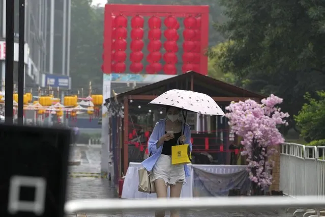 A woman uses an umbrella during a rainy day in Beijing, Sunday, August 14, 2022. (Photo by Ng Han Guan/AP Photo)