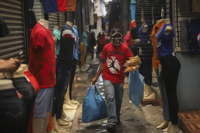 A man, wearing a protective face mask, walks through a popular market in Managua, Nicaragua, Tuesday, April 7, 2020. Restaurants are empty, there's little traffic in the streets and beach tourists are sparse headed into Holy Week despite the government's encouragement for Nicaraguans to go about their normal lives. (Photo by Alfredo Zuniga/AP Photo)