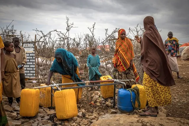 People try to fill water bottles in a displacement camp for people impacted by drought on September 3, 2022 in Baidoa, Somalia. Extreme drought has destroyed crops and seen a hike in food prices, leaving 7 million people (out of a total population of 16 million) at risk of famine in Somalia. (Photo by Ed Ram/Getty Images)