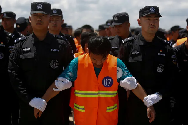 Chinese nationals (in orange vests) who were arrested over a suspected internet scam, are escorted by Chinese police officers before they were deported at Phnom Penh International Airport, in Phnom Penh, Cambodia, October 12, 2017. (Photo by Samrang Pring/Reuters)