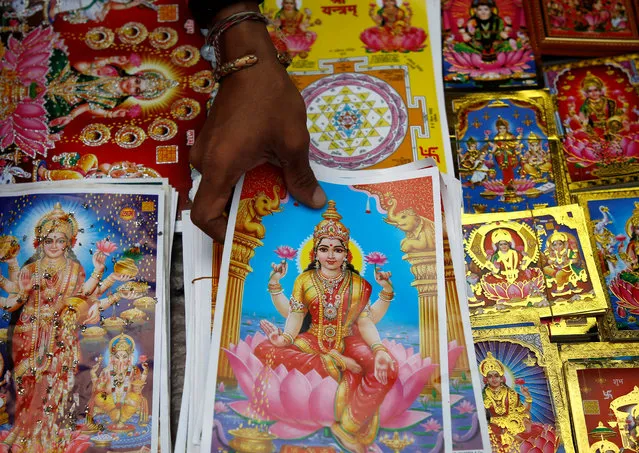 A vendor reach out for the poster of Goddess of Wealth Laxmi, kept on sale for the Tihar festival, also called Diwali, in Kathmandu, Nepal October 15, 2017. (Photo by Navesh Chitrakar/Reuters)