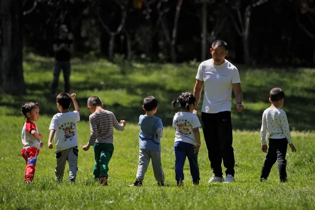 Children accompanied by a man play at a public park as kindergarten and primary schools still remain closed following the new coronavirus outbreak in Beijing, Monday, May 11, 2020. China reported another rise in coronavirus cases Monday, amid government reminders for people to “remain alert and step up personal protection against the virus”. (Photo by Andy Wong/AP Photo)