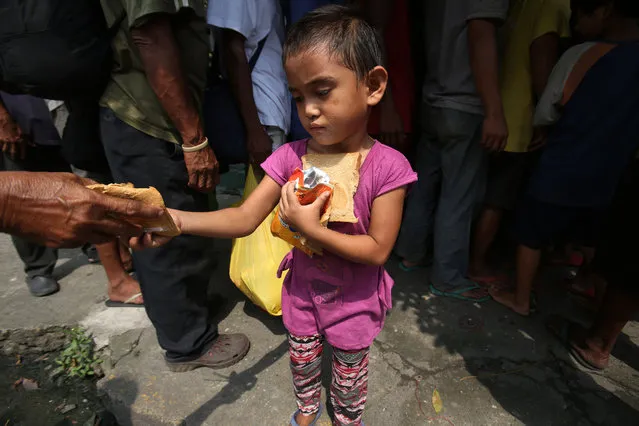 A poor Filipino girl holds bread and drinks she received during a feeding program by Dominican nuns in Manila, Philippines on Wednesday, September 17, 2014. The weekly program gives a free meal to homeless people around the community. (Photo by Aaron Favila/AP Photo)