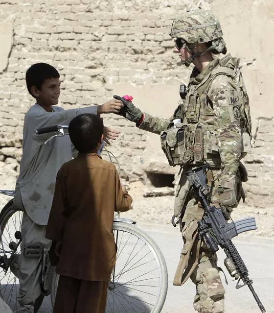 A boy gives a flower to U.S. army soldier SGT Jessica Corona of Task Force Lancer, 563 Military Police Company while on patrol in Kandahar city, southern Afghanistan October 12, 2012. (Photo by Erik De Castro/Reuters)