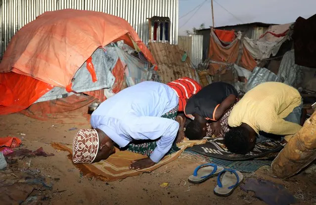 Internally displaced Somali men perform prayers after Iftar (breaking the fast) during the month of Ramadan at the Shabelle makeshift camp in Hodan district of Mogadishu, Somalia on May 8, 2020. (Photo by Feisal Omar/Reuters)