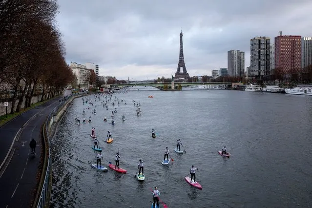 Competitors steer their Stand Up Paddle boards during a race on the Seine river in Paris, Sunday, December 5, 2021. More than 1000 people took part to the competition though the French capital. (Photo by Adrienne Surprenant/AP Photo)