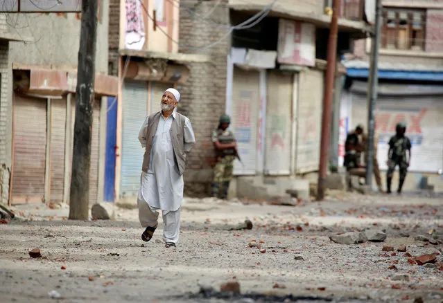 A man walks amid rubble thrown by protestors in Srinagar as security forces enforce a curfew following weeks of violence in Kashmir, August 18, 2016. (Photo by Cathal McNaughton/Reuters)