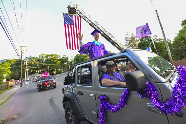 Griffin Waryas, president of the Bellows Falls Union High School's Class of 2020, waves to the crowd of people that gathered to congratulate on Westminster Street, in Bellows Falls, Vt., during the school's graduation parade on Thursday, June 18, 2020. (Photo by Kristopher Radder/The Brattleboro Reformer via AP Photo)
