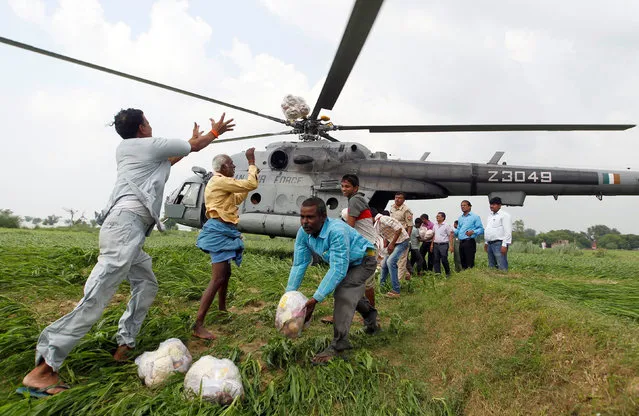 Food parcels are unloaded from an Indian Air Force helicopter to be distributed among those affected by flooding on the outskirts of Allahabad, India, August 25, 2016. (Photo by Jitendra Prakash/Reuters)