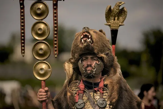 A participant in the Romula Fest historic reenactment event, wearing a Roman legion uniform and a bear fur stands in the village of Resca, Romania, Sunday, September 4, 2022. Members of historic NGOs and volunteers gathered in a field outside a southern Romanian village, once part of the Romula Malva, Roman Empire era city, aiming to raise awareness for history through realistic reenactments of battles between Roman legions and local Dacian tribes. (Photo by Andreea Alexandru/AP Photo)
