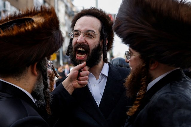 An Ultra-Orthodox Jewish person holds the beard of a man on the street as they celebrate the Jewish holiday of Purim in Bnei Brak, Israel on March 24. 2024. (Photo by Carlos Garcia Rawlins/Reuters)