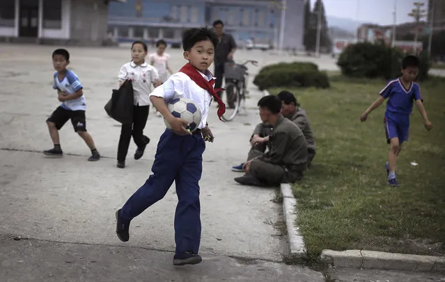 A North Korean schoolboy runs with a soccer ball as he plays with his friends near the pier on Tuesday, June 21, 2016, in Wonsan, North Korea. Wonsan, about 200 kilometers (125 miles) from Pyongyang, is a port city located in Kangwon Province, North Korea along the eastern side of the Korean Peninsula, and was one of the cities chosen to be developed into a summer destination for locals as well as tourists. (Photo by Wong Maye-E/AP Photo)