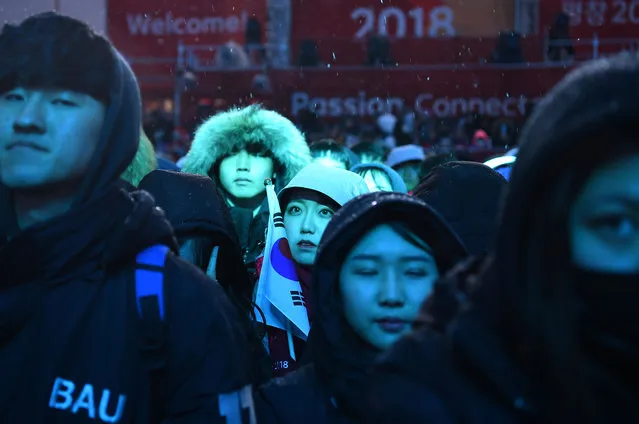 Fans wait under the snow for the start of the medal ceremonies at the Pyeongchang Medals Plaza during the Pyeongchang 2018 Winter Olympic Games in Pyeongchang on February 23, 2018. (Photo by Dimitar Dilkoff/AFP Photo)