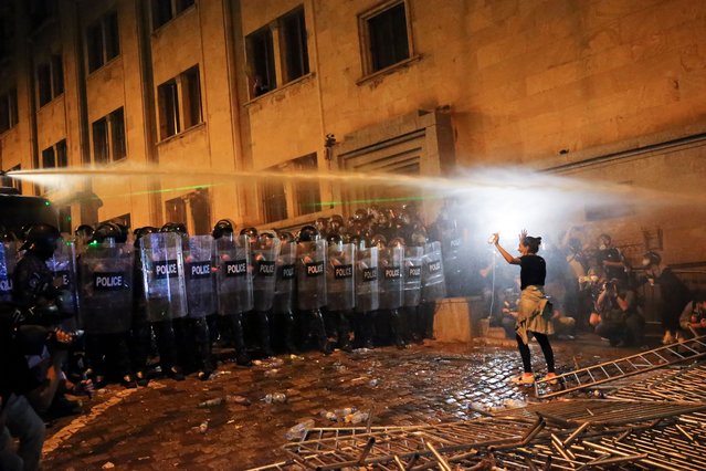 A demonstrator gestures trying to stop riot police during an opposition protest against “the Russian law” near the Parliament building in Tbilisi, Georgia, on Tuesday, April 30, 2024. Clashes erupted between police and opposition demonstrators protesting a new bill intended to track foreign influence that the opposition denounced as Russia-inspired. (Photo by Zurab Tsertsvadze/AP Photo)