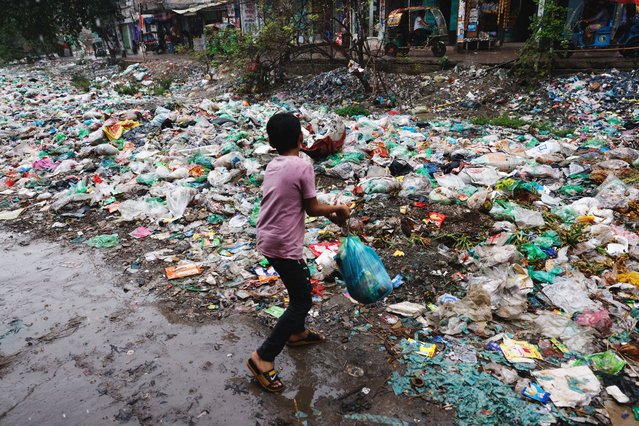 A boy throws a polythene bag full of waste into Shuvadda Canal which is under the pile of plastic waste, in Dhaka, Bangladesh on May 20, 2025. (Photo by Mohammad Ponir Hossain/Reuters)