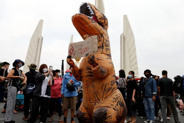 A demonstrator wearing a T-Rex costume carries a sign during a rally to call for the ouster of Prime Minister Prayuth Chan-ocha's government and reforms in the monarchy in Bangkok, Thailand, November 8, 2020. (Photo by Soe Zeya Tun/Reuters)