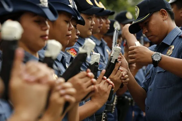 An officer of the Philippine National Police force tapes the muzzle of a gun at a police camp in Taguig City, south of Manila, Philippines, 22 December 2014. (Photo by Francis R. Malasig/EPA)