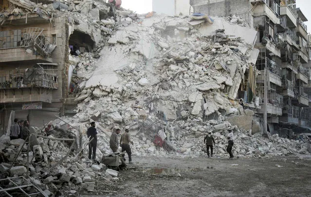 Members of the Syrian Civil Defence, known as the White Helmets, search for victims amid the rubble of a destroyed building following reported air strikes in the rebel-held Qatarji neighbourhood of the northern city of Aleppo, on October 17, 2016. Dozens of civilians were killed as air strikes hammered rebel-held parts of Aleppo early morning, despite Western warnings of potential sanctions against Syria and Russia over attacks on the city. Both Russian and Syrian warplanes are carrying out air strikes over Aleppo in support of a major offensive by regime forces to capture rebel-held parts of the northern city. (Photo by Karam Al-Masri/AFP Photo)
