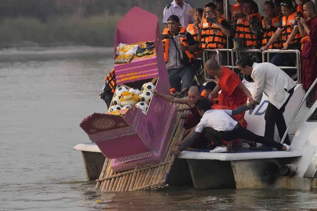 Family members, accompanied by monks and fellow mourners, release the ashes of Duangphet Phromthep in a makeshift boat, along with soccer balls and some of his prized possessions, into the Mekong River in Chiang Rai Province Thailand, Monday, March 6, 2023. Duangphet was one of the 12 boys rescued from a flooded cave in 2018. He died in the U.K. last month. (Phoot by Sakchai Lalit/AP Photo)