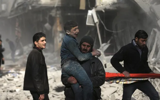 A man carries an injured civilian at a site hit by what activists said was an air strike by forces of Syria's President Bashar al-Assad in the Duma neighbourhood of Damascus December 27, 2014. (Photo by Bassam Khabieh/Reuters)