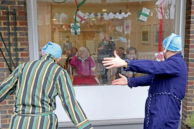 Award winning “masters of the absurd” Dan Lees and Neil Frost of Mad Etiquette perform through the front window glass for residents at the Spring Lane Nursing Home on December 18, 2020 in London, England. “Little Window Therapies” is Alexandra Palace's Creative Learning Team. (Photo by Chris Jackson/Getty Images)
