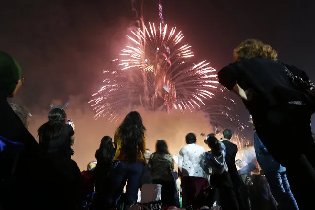 People look at a firework display during a New Year celebration on January 1, 2015 in Dubai. (Photo by Karim Sahib/AFP Photo)