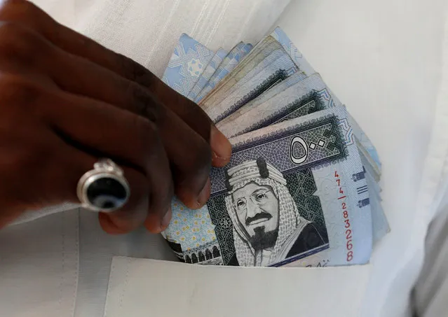 A Saudi man shows Saudi riyal banknotes at a money exchange shop, in Riyadh, Saudi Arabia, January 20, 2016. (Photo by Faisal Al Nasser/Reuters)