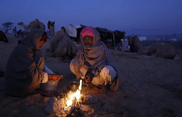 Indian cattle herders warm themselves around a bonfire early morning at the annual cattle fair in Pushkar, in the western Indian state of Rajasthan, Friday, November 20, 2015. Pushkar is a popular Hindu pilgrimage spot that is also frequented by foreign tourists who come to the town for its annual cattle fair. (Photo by Deepak Sharma/AP Photo)