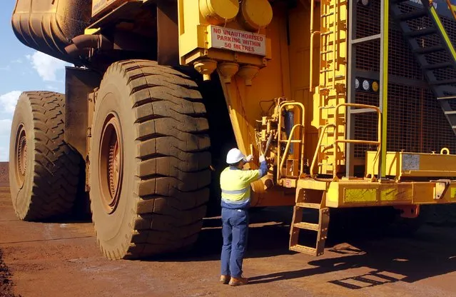 A worker checks a truck loaded with iron ore at the Fortescue Metals Group (FMG) Christmas Creek iron ore mine located south of Port Hedland in the Pilbara region of Western Australia, November 17, 2015. (Photo by Jim Regan/Reuters)