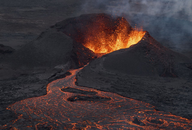 A lava flow is seen at the base of the crater, background, which is still very active after a volcanic eruption around 6km north of Grindavik on the Reykjanes Peninsula, in Iceland, Wednesday, July 23, 2025. (Phoot by Marco di Marco/AP Photo)