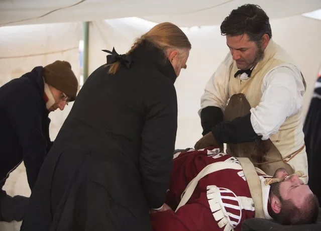 Albert Roberts of Nashville, Tennessee plays a doctor attempting to save an injured American fighter, Mark Miller of West Monroe, Louisiana, following a reenactment of the Battle of New Orleans in the War of 1812, marking its bicentennial in Chalmette, Louisiana January 10, 2015. (Photo by Lee Celano/Reuters)