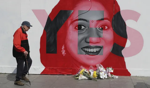 A man walks past a mural showing Savita Halappanavar, a 31-year-old Indian dentist who had sought and been denied an abortion before she died after a miscarriage in a Galway hospital, with the word YES over it, in Dublin, Ireland, on the day of a referendum on the 8th amendment of the constitution. The referendum on whether to repeal the country's strict anti-abortion law is being seen by anti-abortion activists as a last-ditch stand against what they view as a European norm of abortion-on-demand, while for pro-abortion rights advocates, it is a fundamental moment for declaring an Irish woman's right to choose. (Photo by Niall Carson/PA Wire via AP Photo)
