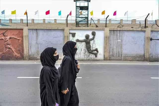 Muslim students walk outside wall of a newly renovated sports stadium ahead of G20 tourism working group meeting in Srinagar, Indian controlled Kashmir, Tuesday, May 16, 2023. (Photo by Mukhtar Khan/AP Photo)