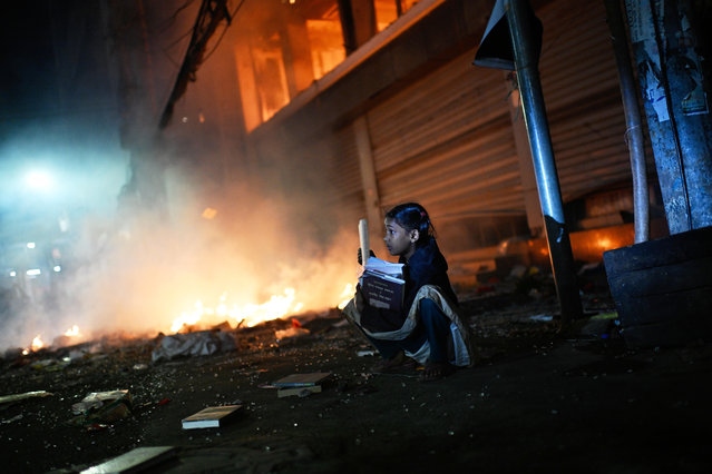 A girl rescues books from a shop near the premises of the Prothom Alo daily newspaper which was set on fire by angry protesters after news reached the country from Singapore of the death of a prominent activist Sharif Osman Hadi, in Dhaka, Bangladesh, Friday, December 19, 2025. (Photo by Mahmud Hossain Opu/AP Photo)